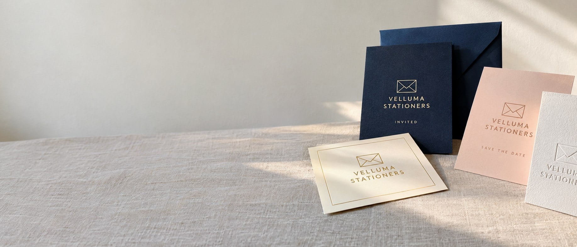 Custom printed and foil-stamped invitations with envelopes on a linen-covered table